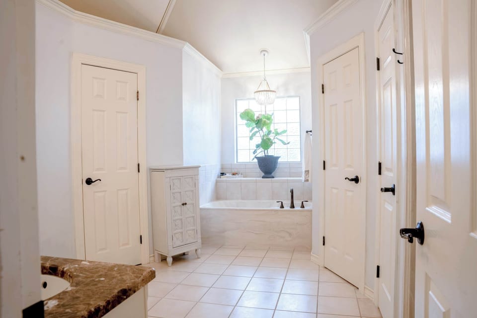 The primary bath: a soaking tub under the window and storage all around.