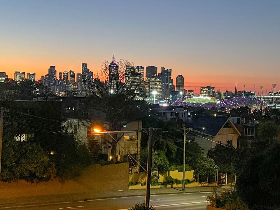 Take in the stunning Melbourne skyline at dusk, with glowing city lights and a vibrant sunset view right from your balcony