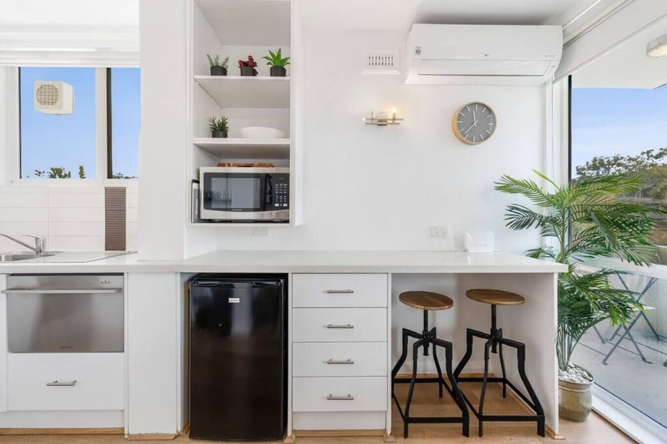 Start your mornings at the cozy breakfast bar, fully equipped with a mini fridge, microwave, and stylish seating beside sunny balcony views