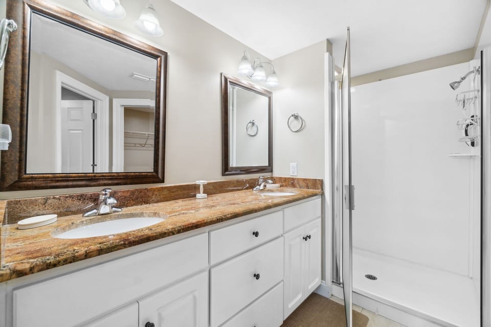 Clean bathroom w/ a wood-toned vanity, sink & mirror — simple & well-lit.