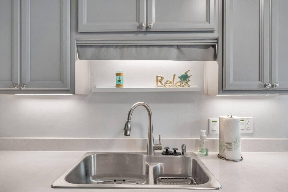 Clean sink area w/ bright lighting and simple finishes that keep things fresh.