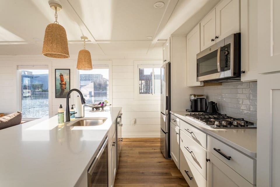 Modern galley kitchen with a four-burner gas stove, quartz island, dishwasher, and waterfront windows letting in natural Baltimore light.