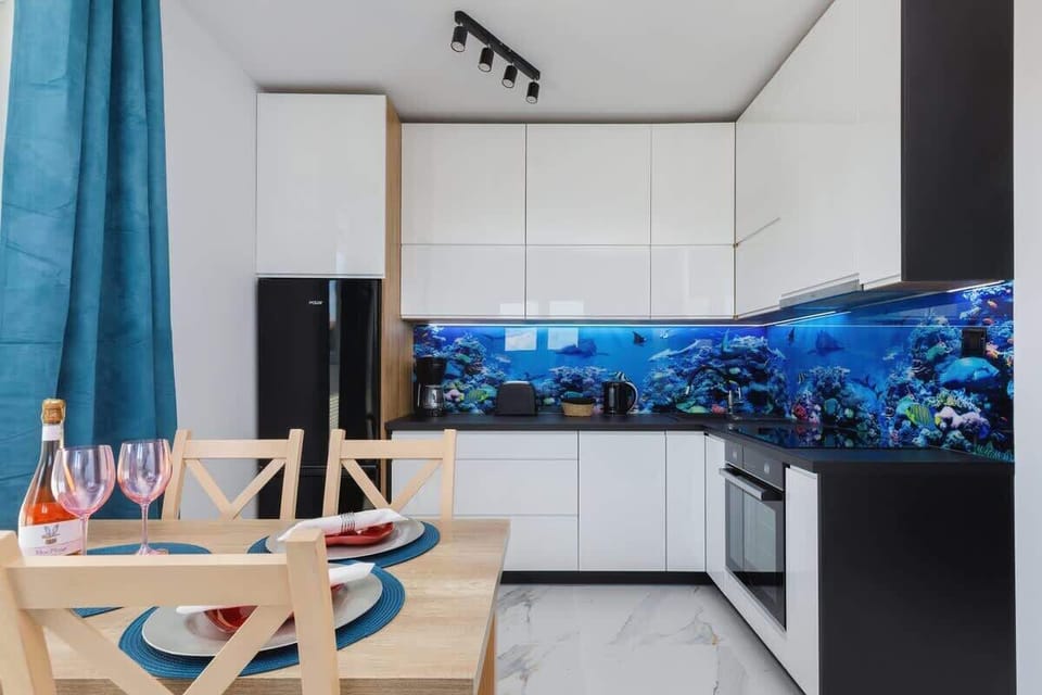A compact and functional kitchen with modern appliances and a unique aquatic-themed backsplash for a fresh look.
