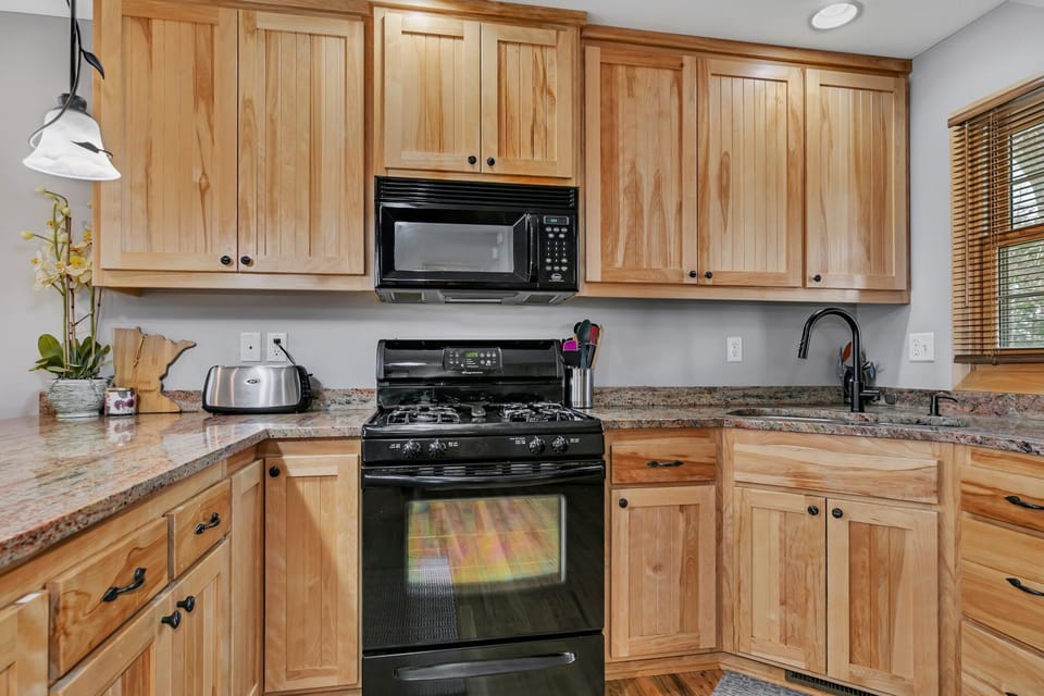 Kitchen area with sink, stove, microwave, and toaster