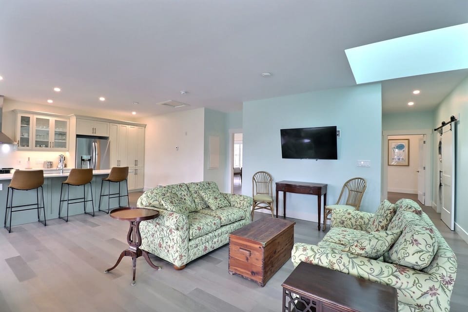 Living space with smart TV, cupola lighting, and hallway to master bedroom with washer/dryer hidden by barn door hardware