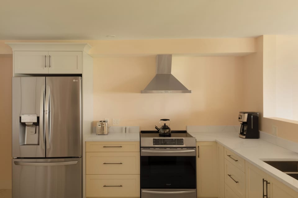 Kitchen with 36' French door refrigerator and induction cooktop stove and adjacent pantry.
