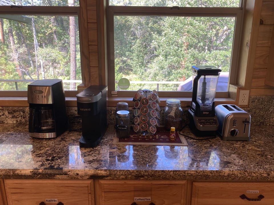 Coffee bar has coffee pot, Keurig, milk frother, coffee and pods. 