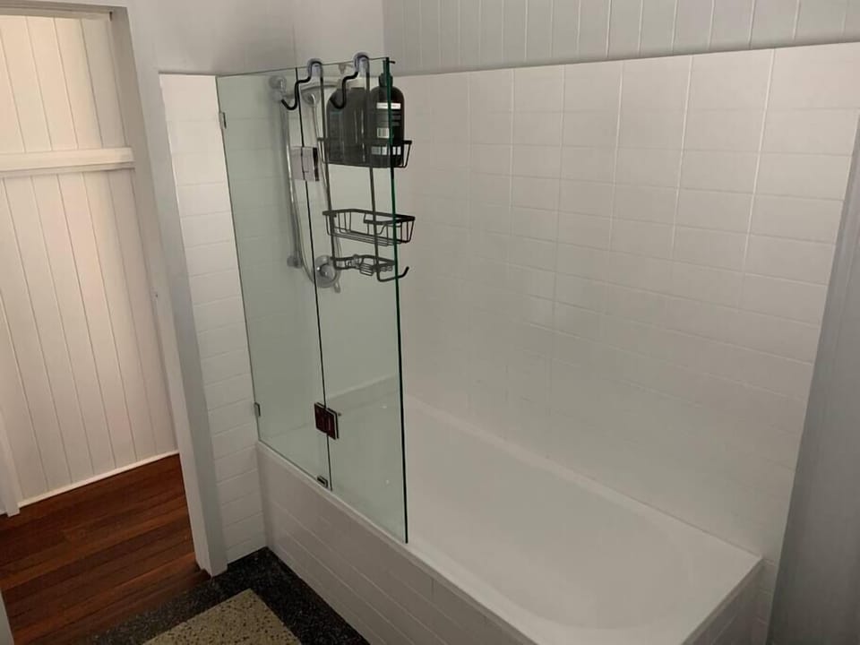 Shower over full-size bath. Original 1920's black terrazo flooring. 
