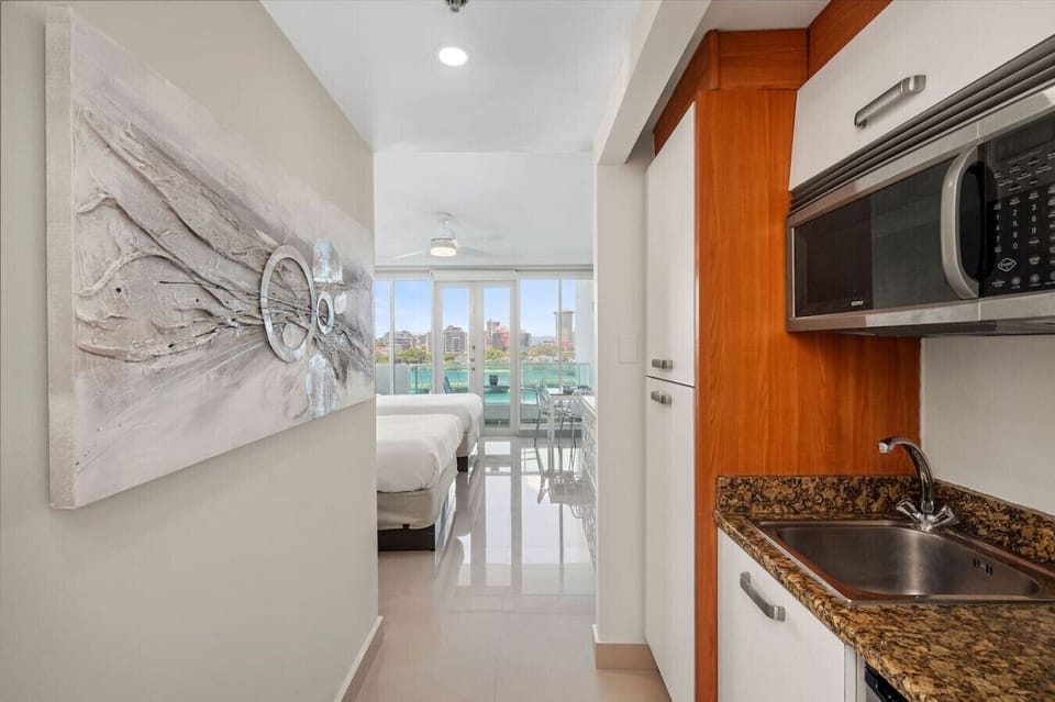 Compact kitchen area with granite countertops leading to a bright bedroom with city views.