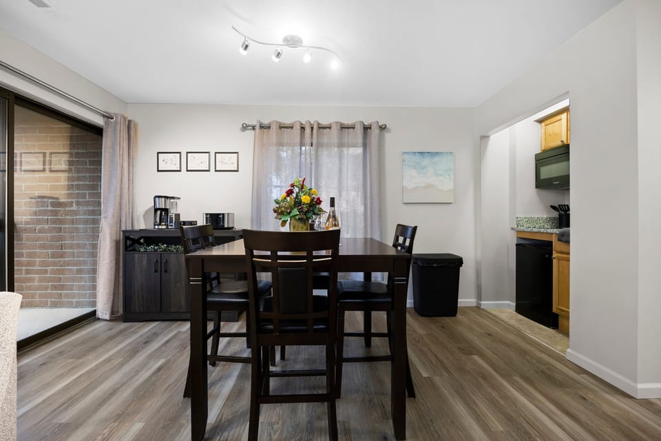 A unit featuring a dining table, with a left-side balcony offering a picturesque lake view and a compact kitchen on the right.