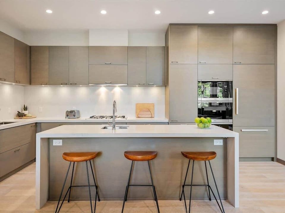 - Kitchen island with bar seating for casual dining or morning coffee  
- Open layout connects kitchen, living, and dining for easy flow  
- Bright lighting highlights sleek finishes and inviting details  
