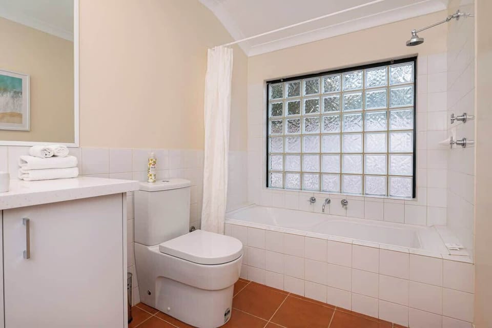 The bright family bathroom, featuring a full-sized bath and frosted glass window, provides a refreshing space to unwind.