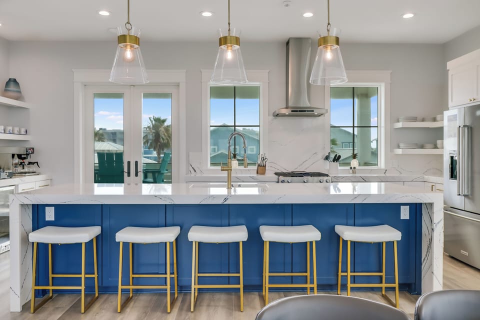 Your modern kitchen features a stunning blue island with marble countertops and gold accents, perfect for cooking memorable meals together.