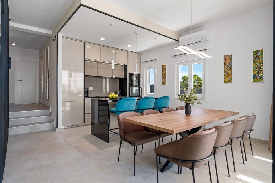 Kitchen island with 3 chairs, a dining table for 8, a step lower is a living room 