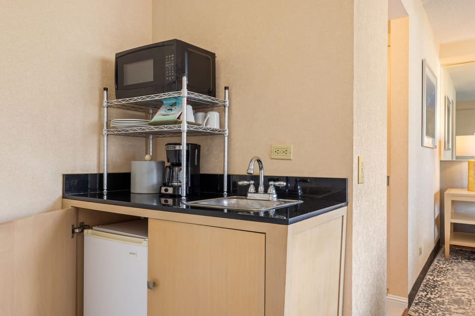 Your compact kitchenette has everything you need—microwave, coffee maker, and mini fridge tucked beneath the sleek counter—perfect for easy snacks and morning coffee in your suite.