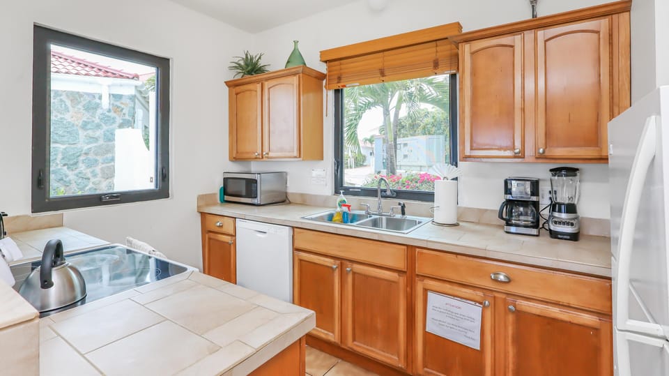 A stainless steel kettle sits on the glass electric stove next to a microwave and dishwasher.