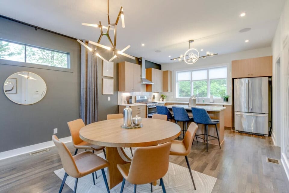 Dining area with round wooden table, brown leather chairs, and open-concept kitchen beyond