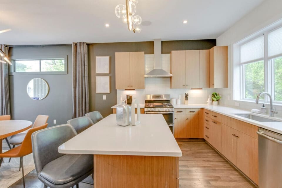 Kitchen featuring warm wood cabinets, white quartz island, range with hood vent, and circular mirror accent