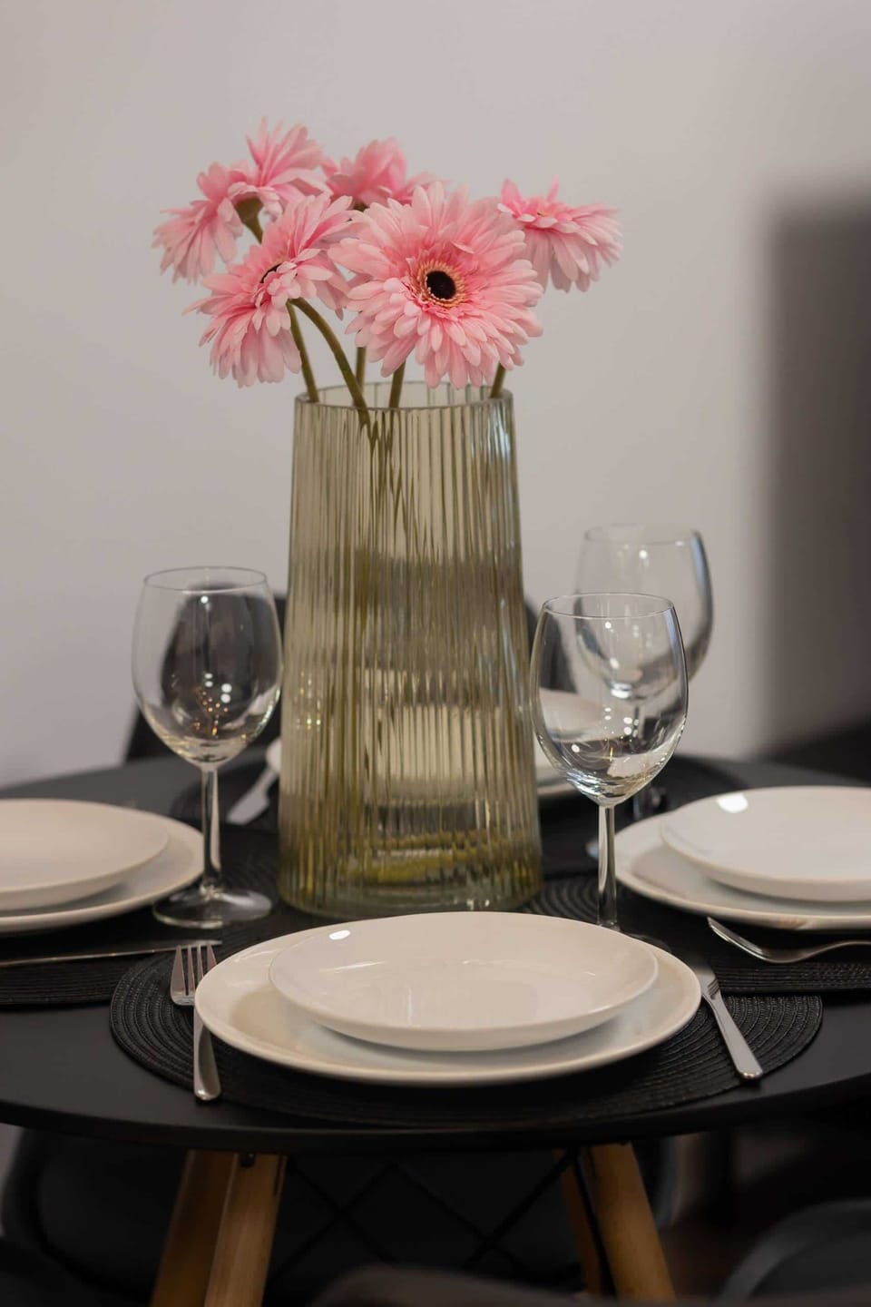 A close-up of the dining table with elegant settings, including a vase with pink flowers for a charming accent.