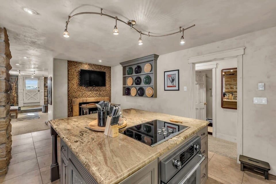 The lovely kitchen features a spacious kitchen island with four bar stools, an additional tall table with seating for four, and the dual-sided fireplace.