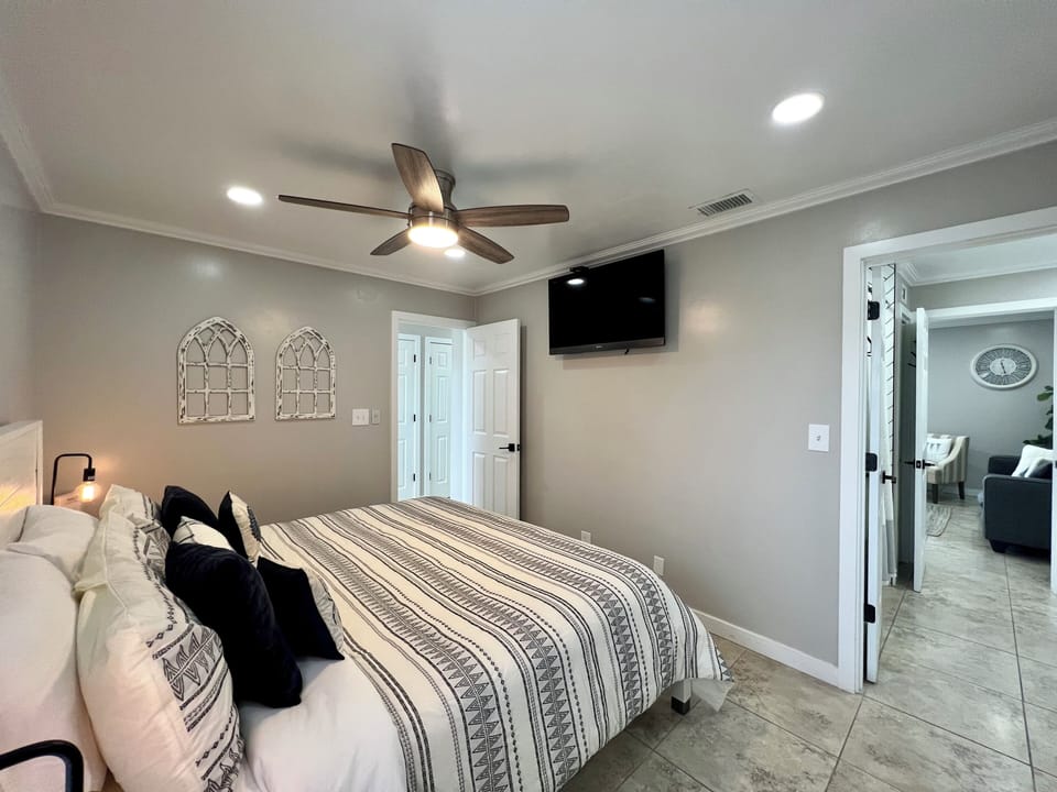 Unwind in your serene bedroom featuring a ceiling fan and wall-mounted TV for perfect comfort after exploring.