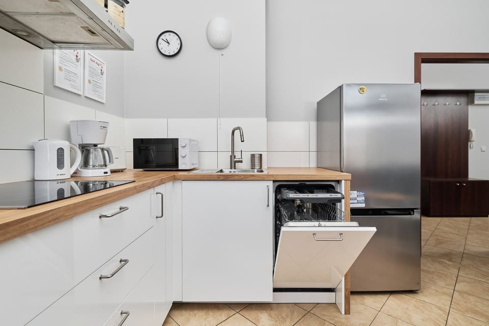 A modern kitchen with white cabinets, tiled floors, and a small round table with chairs.