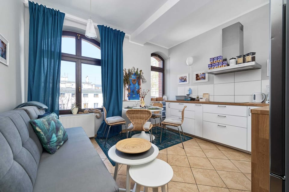 A modern living room space with a small round dining table, a gray couch, and a large window.