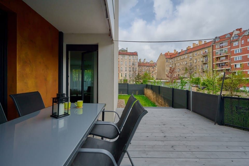 An inviting outdoor patio with a table, chairs, and a view of lush greenery.
