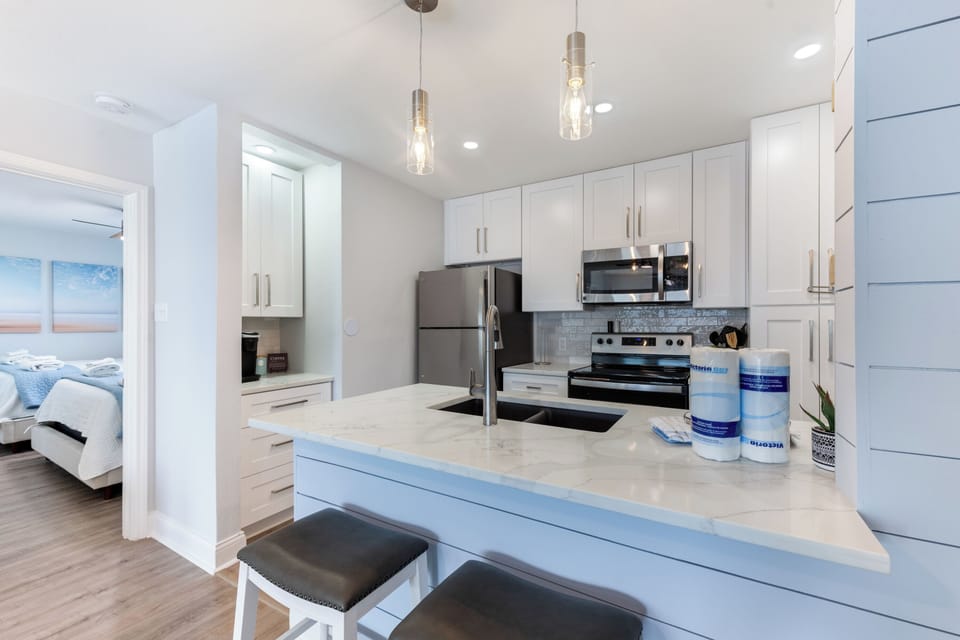 Your modern kitchen features gleaming white cabinets, quartz countertops, and stainless steel appliances—perfect for preparing meals during your stay.