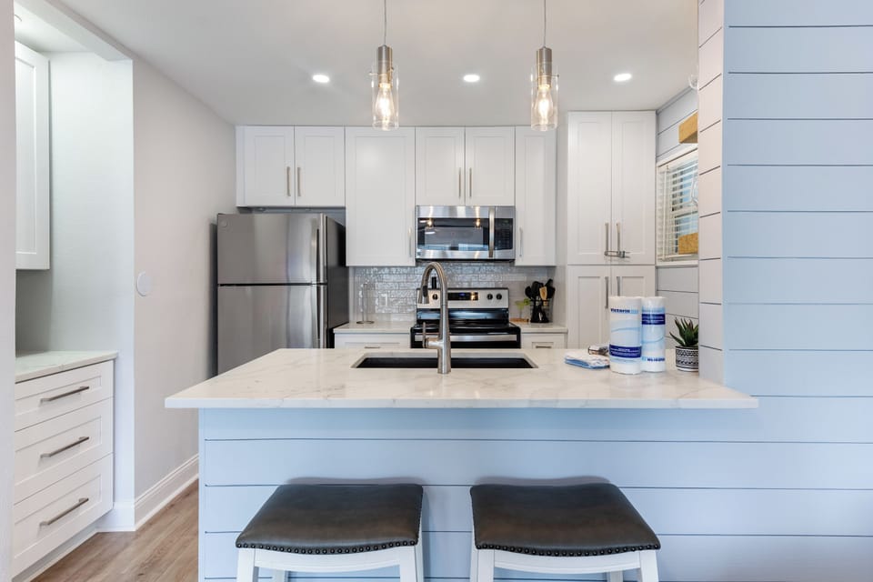 Your modern kitchen awaits with gleaming countertops, stainless steel appliances, and breakfast bar seating for morning coffee moments.