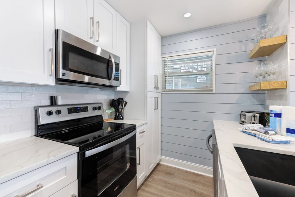 Your fully equipped kitchen awaits with modern appliances, gleaming countertops, and charming shiplap walls that create the perfect backdrop for memorable meals.