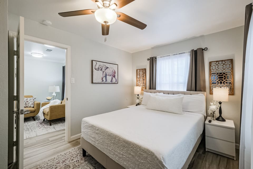 Bedroom next to living area with queen sized bed, walk-in closet, hangers, and smart TV