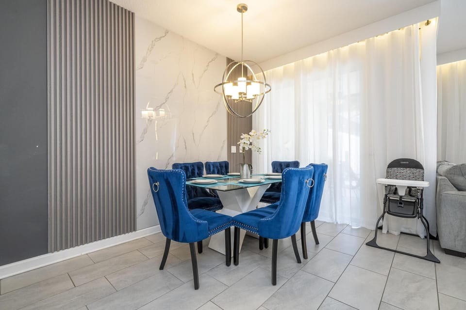 Elegant dining room (Sits 8) with vibrant blue chairs and modern chandelier