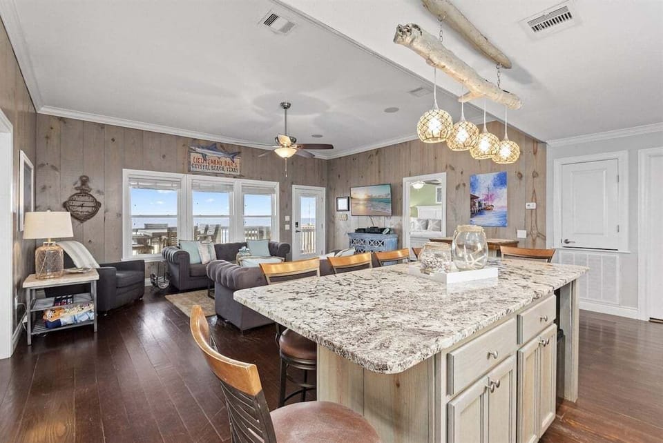 Granite kitchen island with bar seating, pendant lights, open living room views, and coastal vacation home layout.