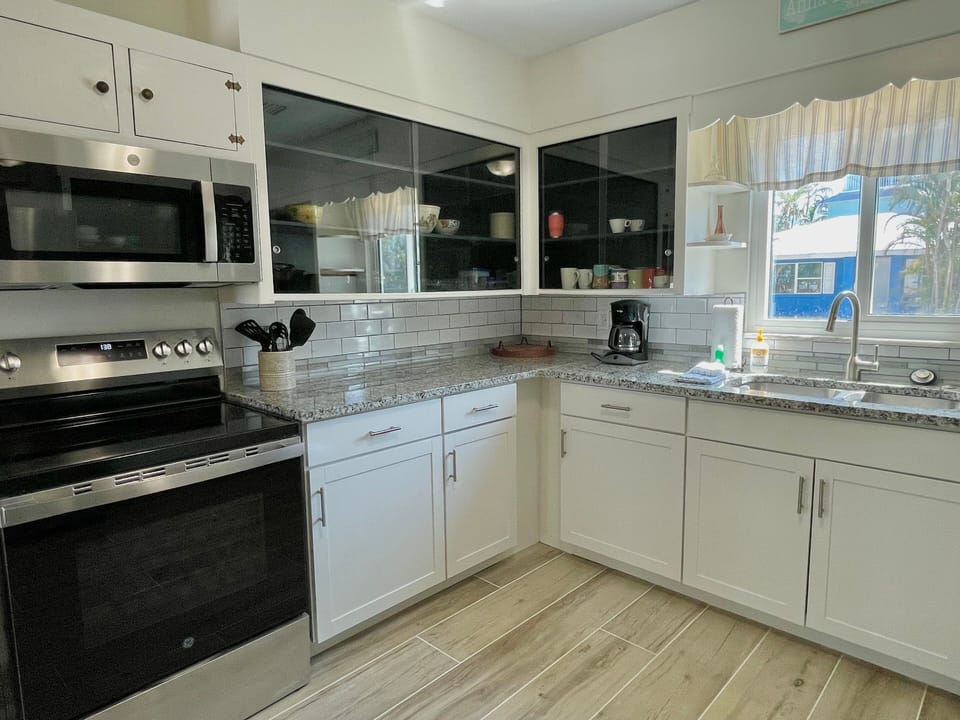 Kitchen with white cabinets, oven, stainless microwave, and tile backsplash