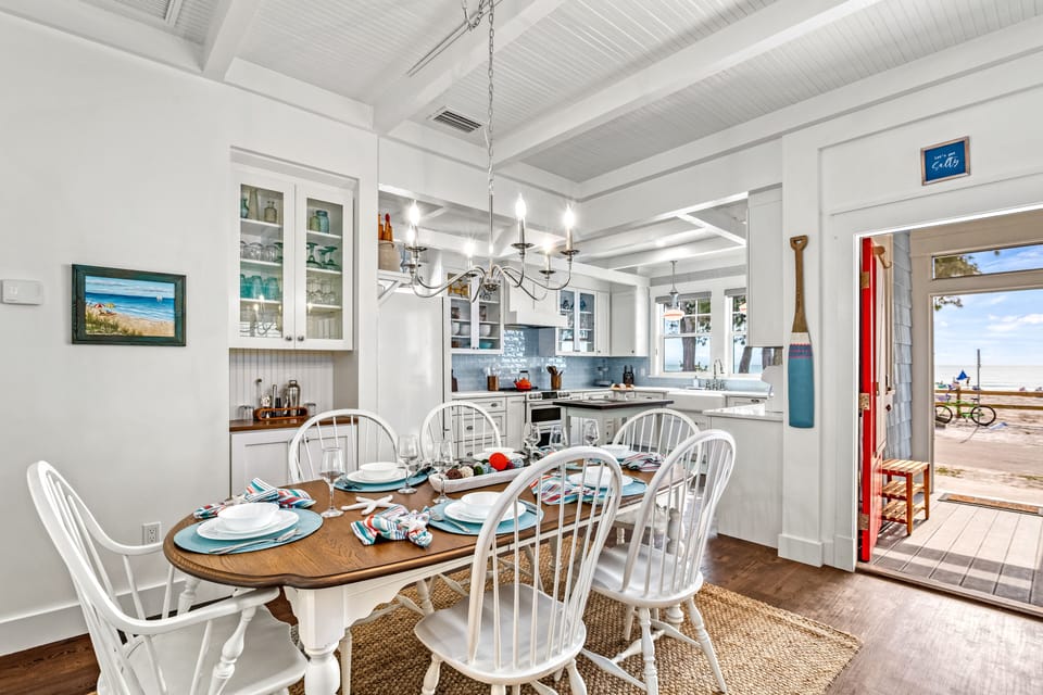 Dining with kitchen in view and door open to outside.