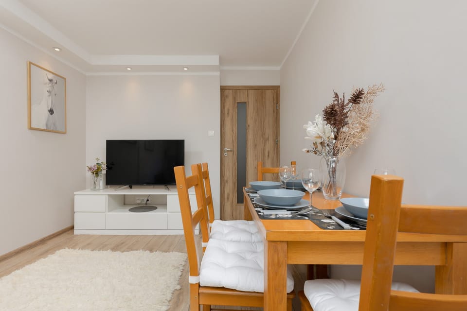 A wooden dining table set for four, with minimalistic decor and neutral tones for a welcoming atmosphere.