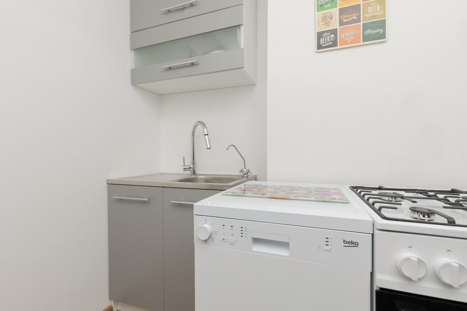 A compact kitchen area with a microwave, cabinets, and a clean, modern design, featuring light tones.