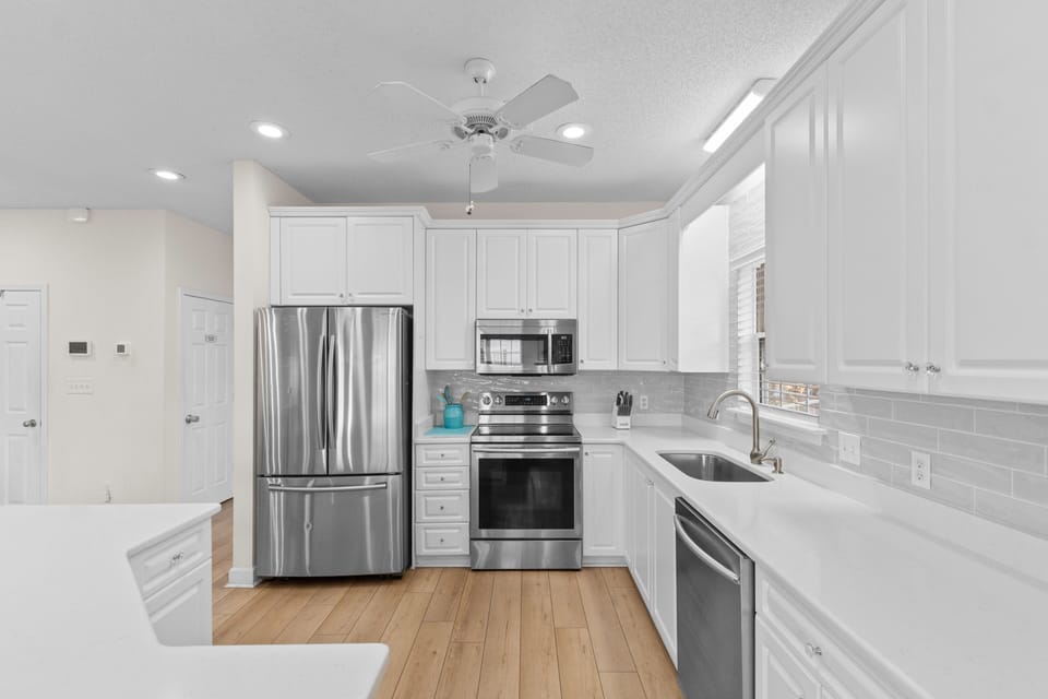 Cook your favorite meals in this bright, modern kitchen featuring stainless steel appliances and pristine white cabinetry.