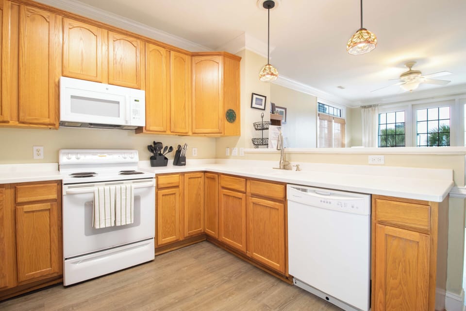 Your bright kitchen features warm wood cabinets, white appliances, and a breakfast bar opening to the living area.