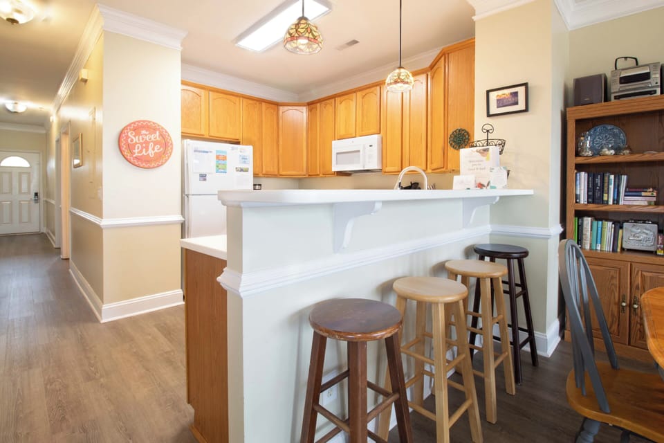 Your fully equipped kitchen features warm wood cabinetry, modern appliances, and a breakfast bar where you can enjoy morning coffee together.