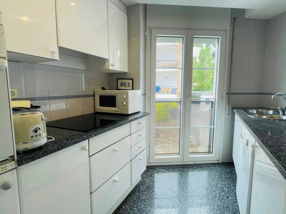 This bright, fully equipped kitchen boasts modern white cabinetry and dark granite countertops, offering a stylish and functional space for preparing meals.