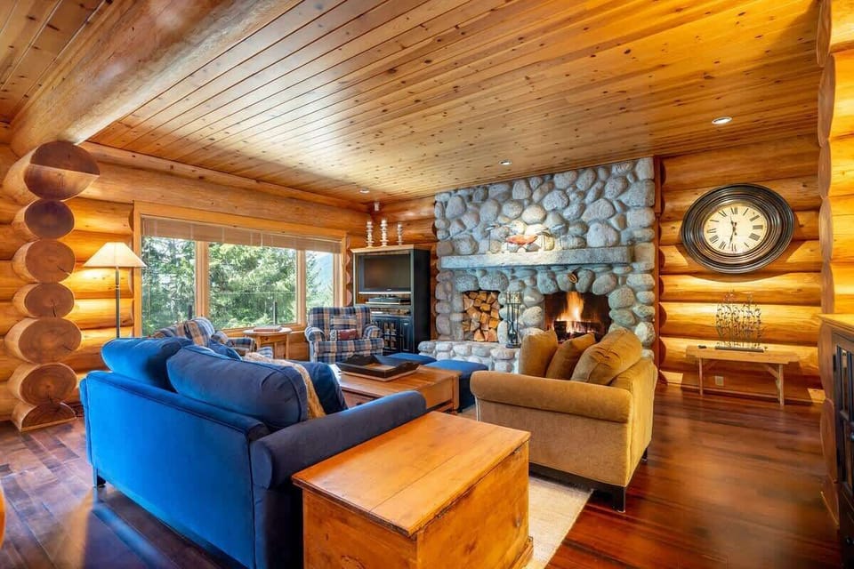 - Inviting log living room with bright forest views and stone hearth  
- Plush couches and rustic beams create alpine warmth  
- Perfect cabin lounge for relaxing and connecting with nature  