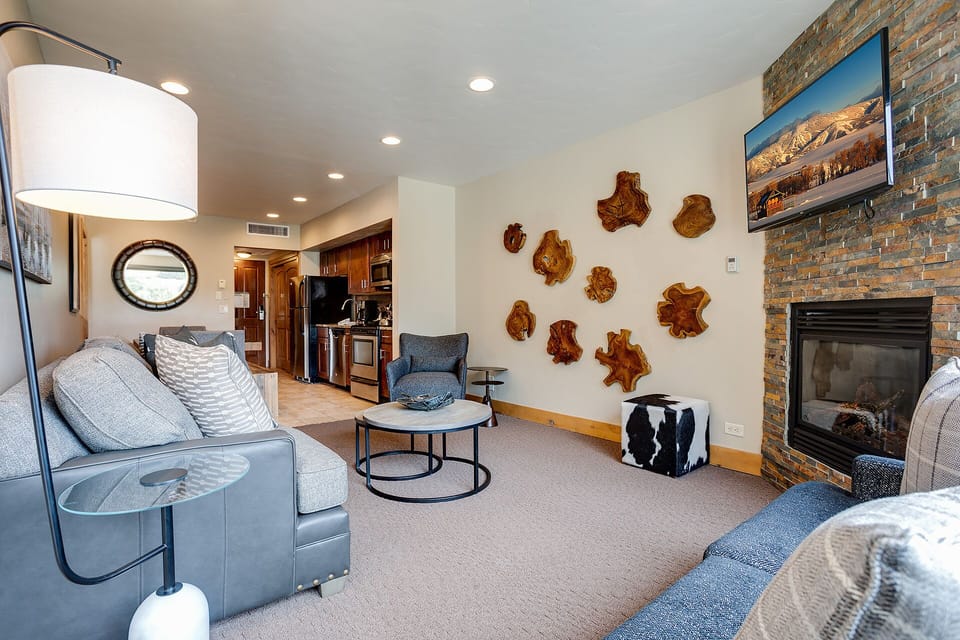 Relax in your thoughtfully designed living space, where warm wood art meets cozy seating by a crackling fireplace.
