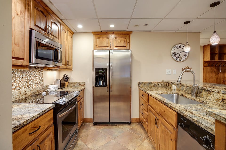 Cook memorable meals in your fully equipped gourmet kitchen featuring granite counters, stainless steel appliances, and warm wood cabinetry.