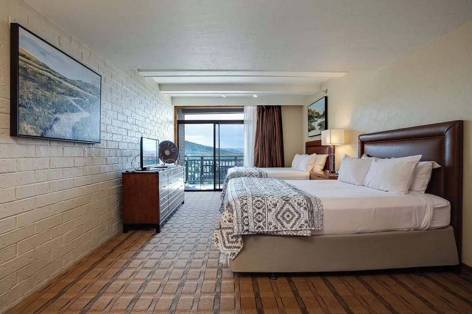 Unwind in your stylish bedroom featuring crisp linens, mountain views, and modern amenities for the perfect retreat.