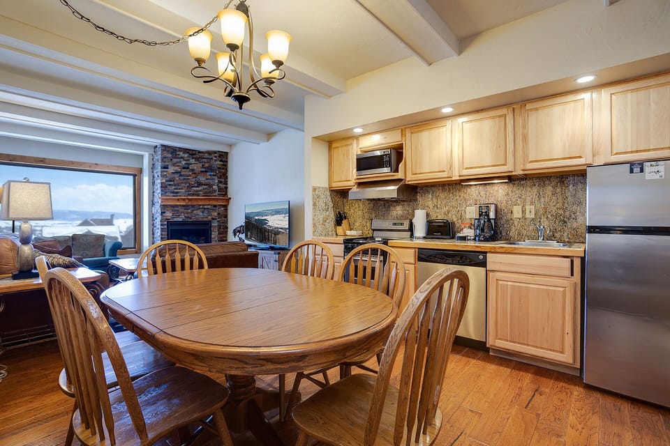 Your spacious kitchen invites family meals with warm wood finishes, granite counters, and mountain views through expansive windows.