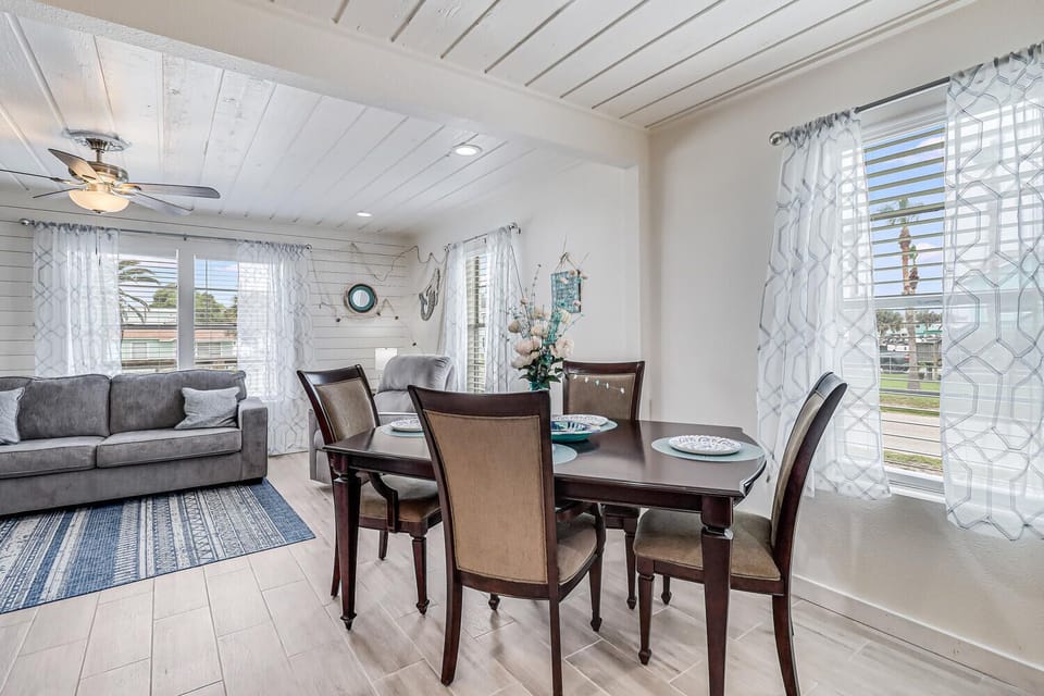 Your bright open living space combines elegant dining with cozy lounging beneath charming white wood beams and nautical touches.
