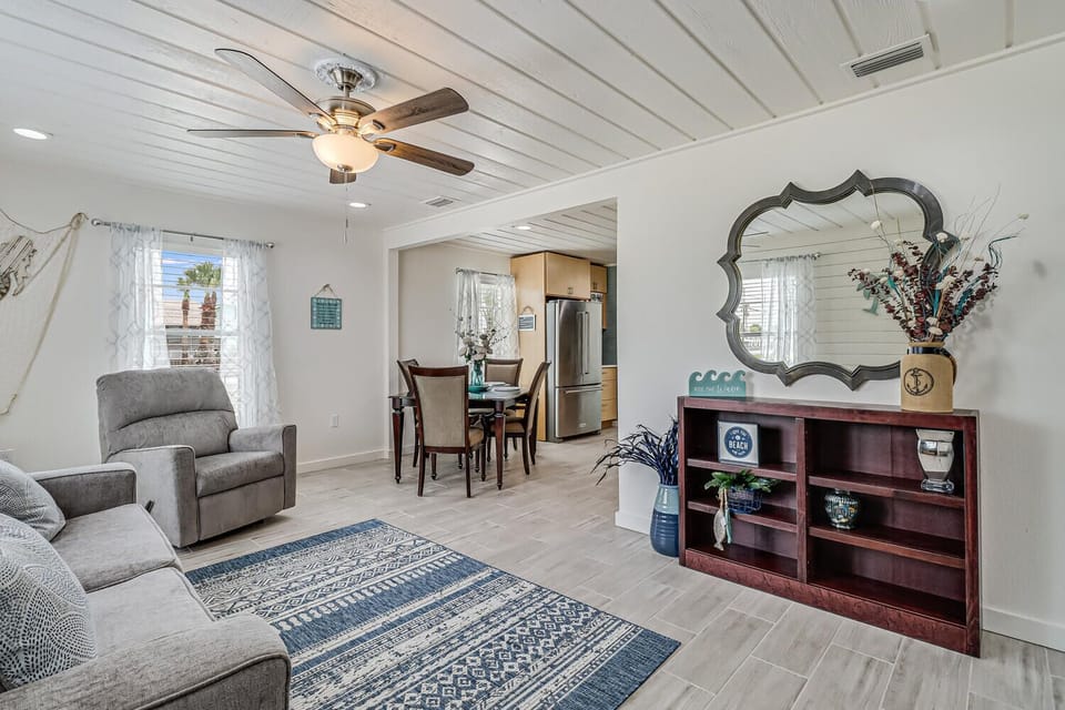 Relax in your spacious living room with plank ceilings, coastal decor, and an open layout connecting to the dining area and kitchen.