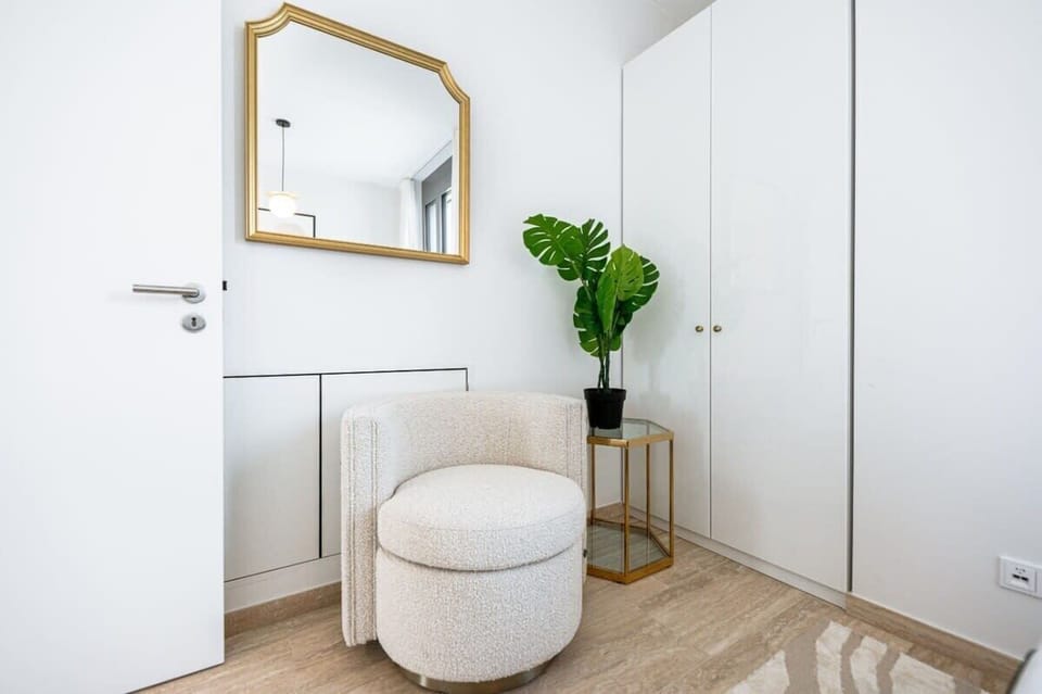 Charming entryway with a bold gold mirror, plush ottoman, and thoughtful touches to welcome you in style
